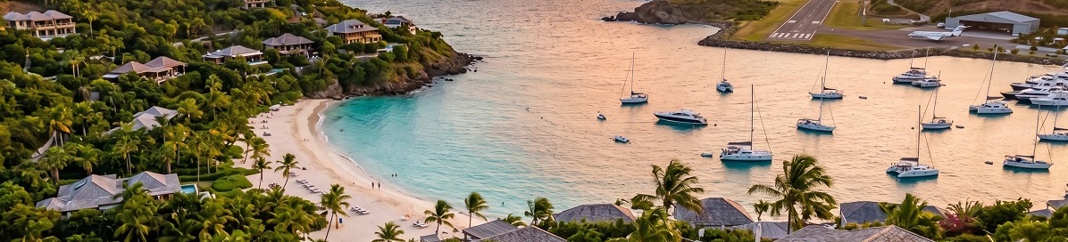 Luxury villas overlooking a tropical bay with yachts and a nearby airport runway at sunset