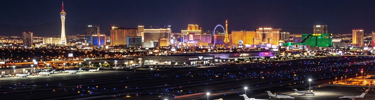 Private jets parked at Harry Reid International Airport with the Las Vegas Strip at night