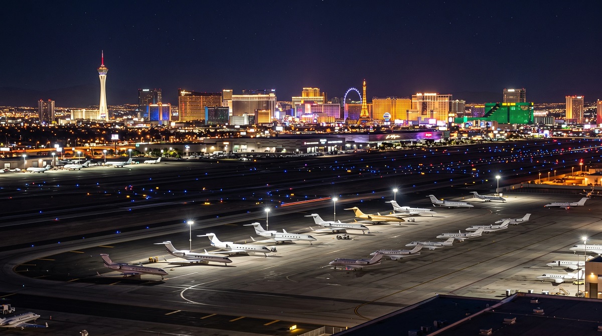 Private jets parked at Harry Reid International Airport with the Las Vegas Strip at night
